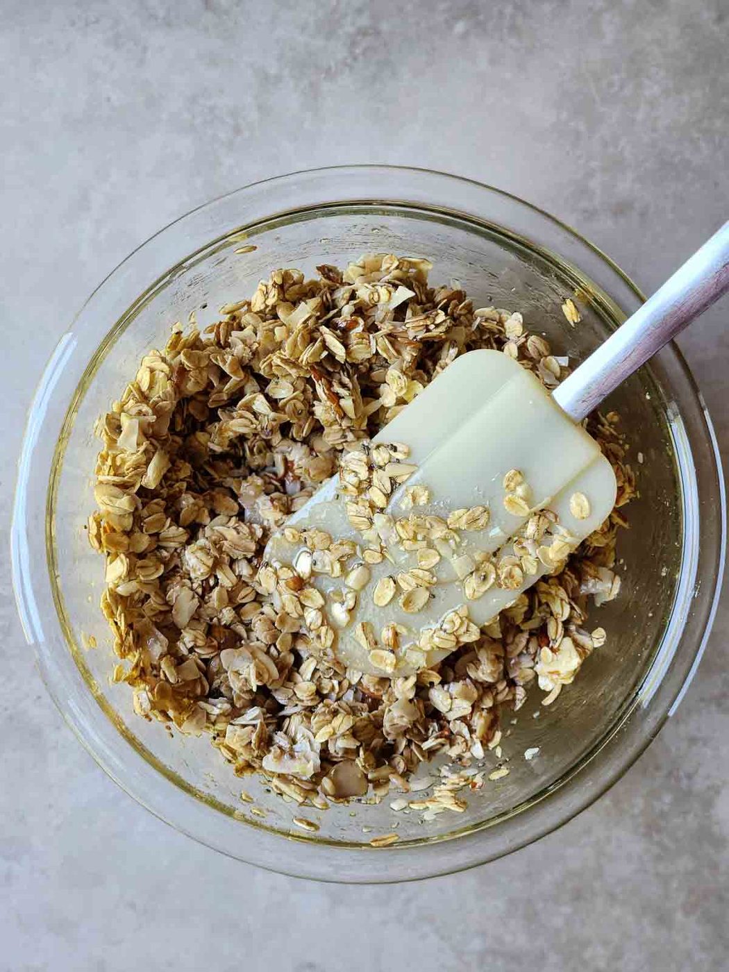 Mixed ingredients in a clear bowl with a spatula in it.