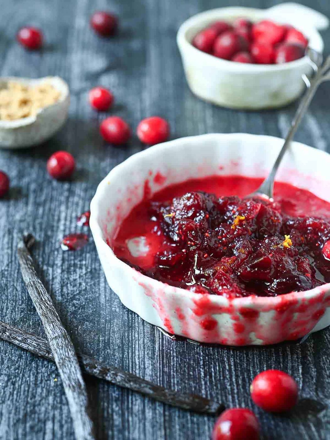 Half-eaten bowl of cranberry compote with vanilla beans in a white bowl.