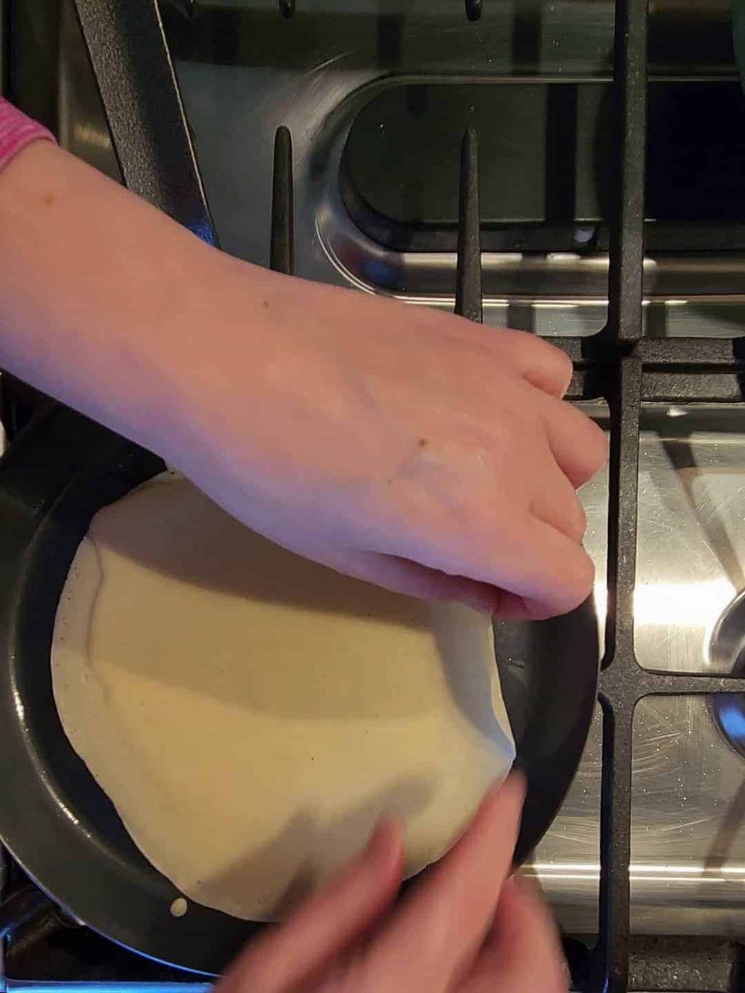 Getting ready to flip lemon ricotta crepes with hands.