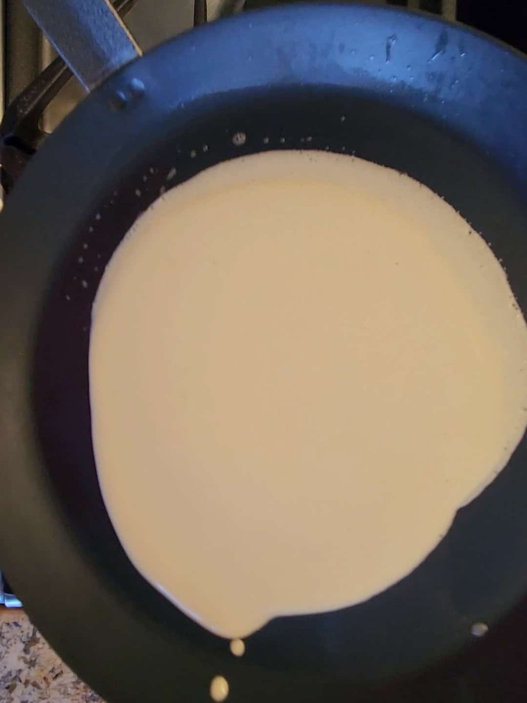 Swirling crepe batter in a pan for lemon ricotta crepes.
