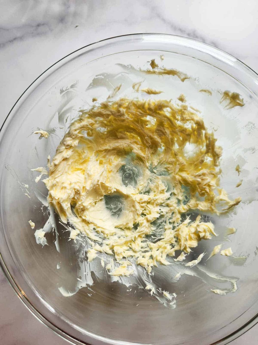 Butter being whipped in a glass bowl.