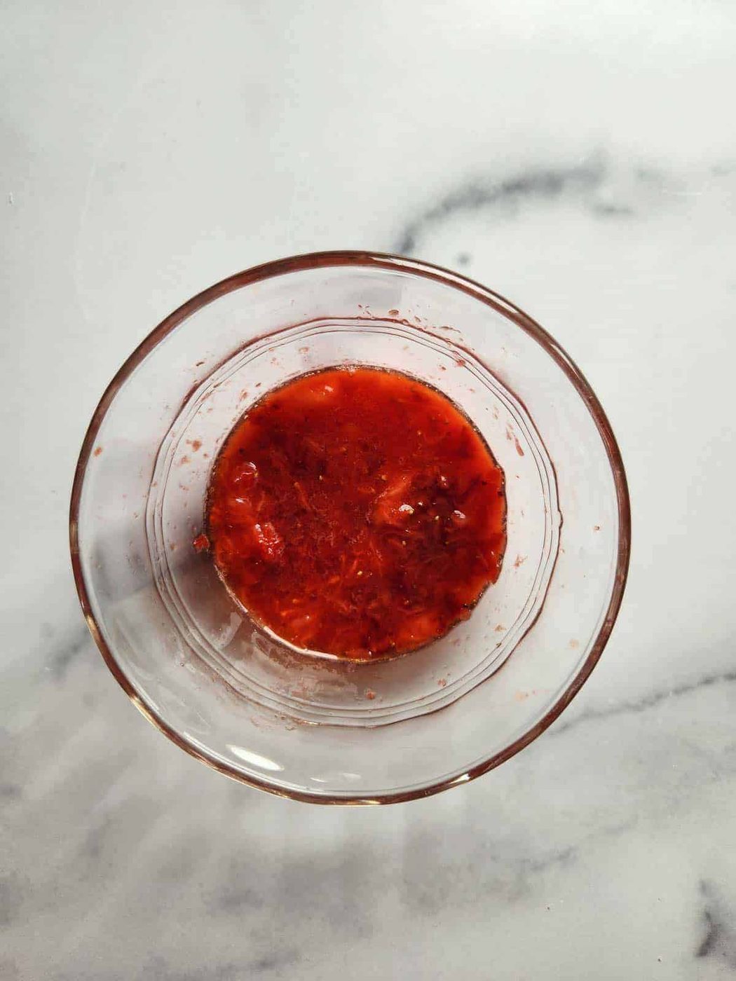 Clear bowl of mashed strawberries.