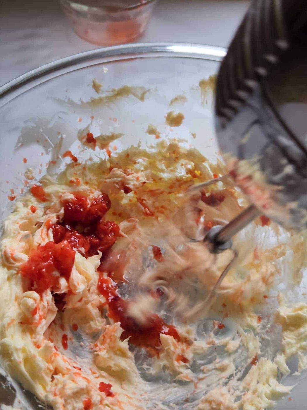 Strawberries being mixed into butter with an electric beater.
