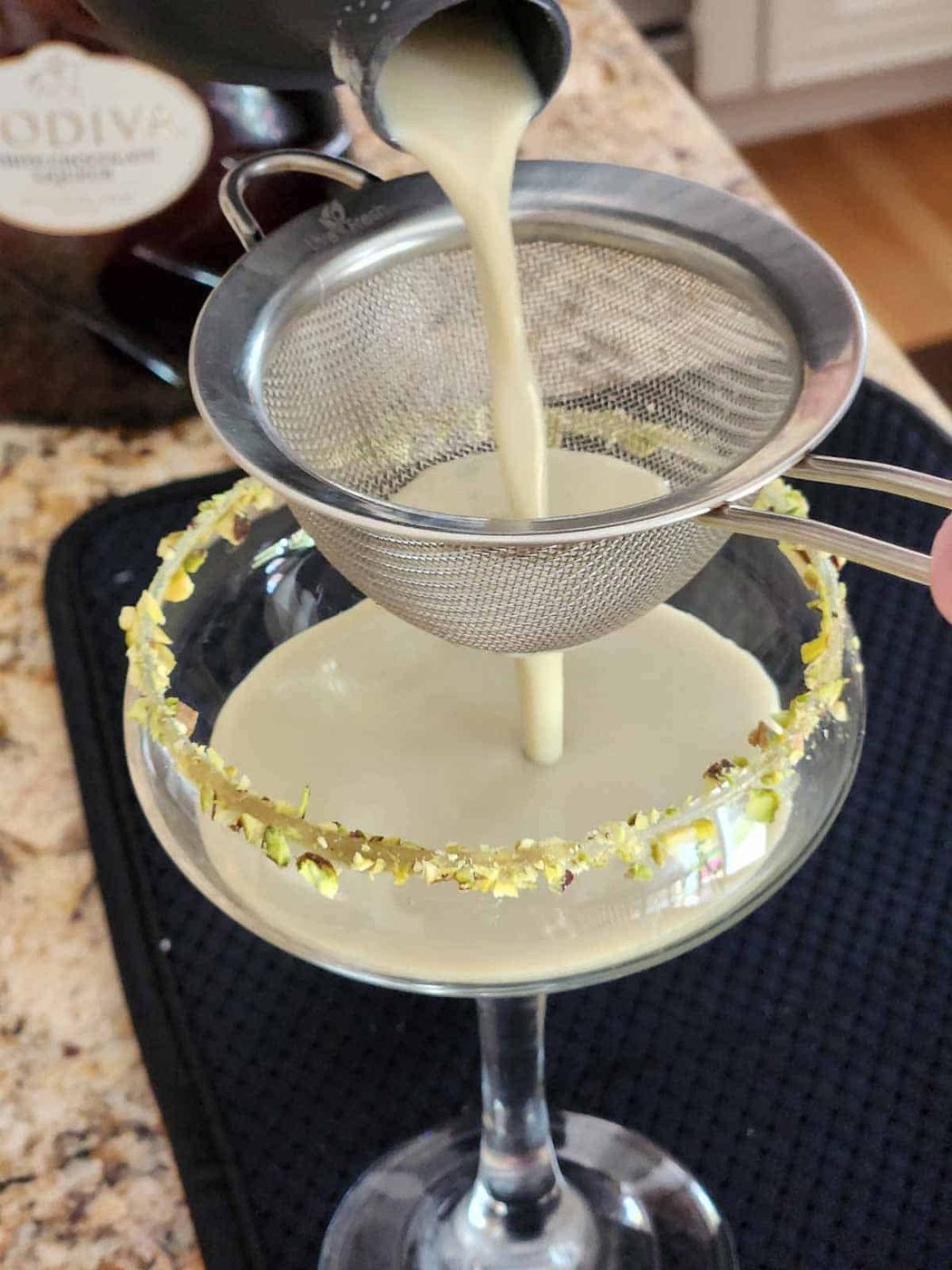 Pistachio martini being strained into a glass.