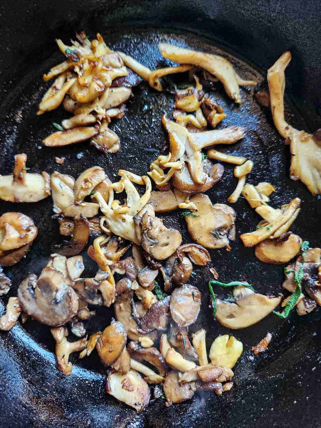 Overhead of sautéed mushrooms in a black skillet.