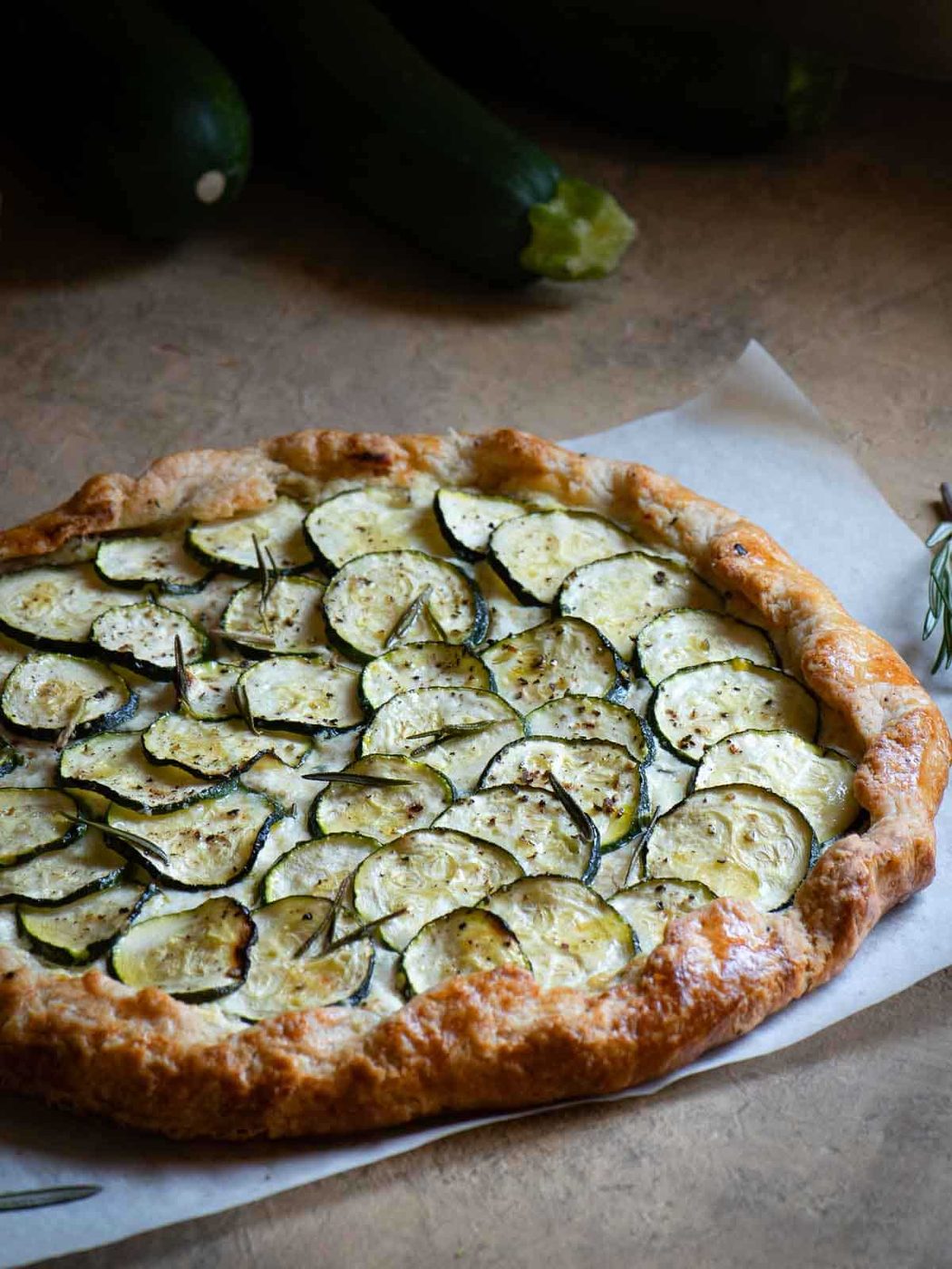 Zucchini gallete on a brown surface with zucchini in the background.