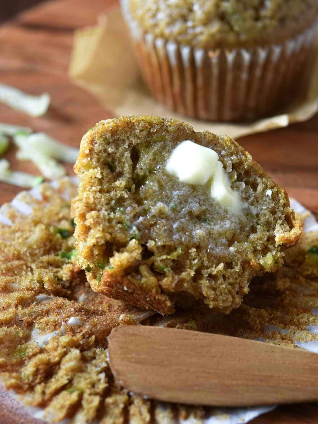 Muffins cut open with melted butter dripping on in on a wood surface.