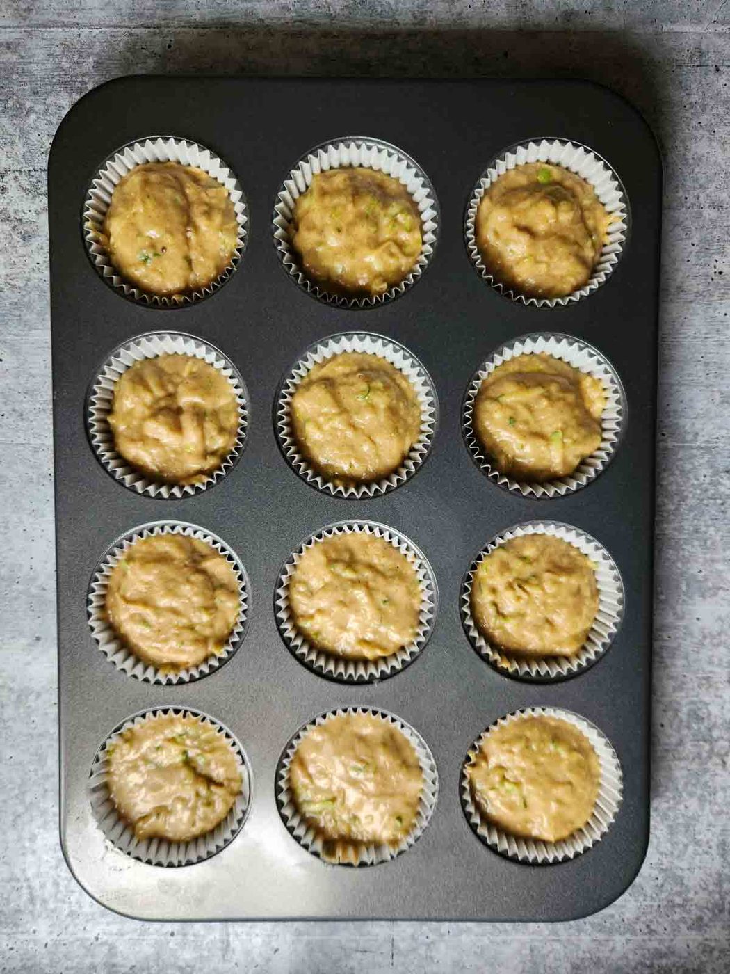 Muffin batter in a 12 cup metal muffin tin.