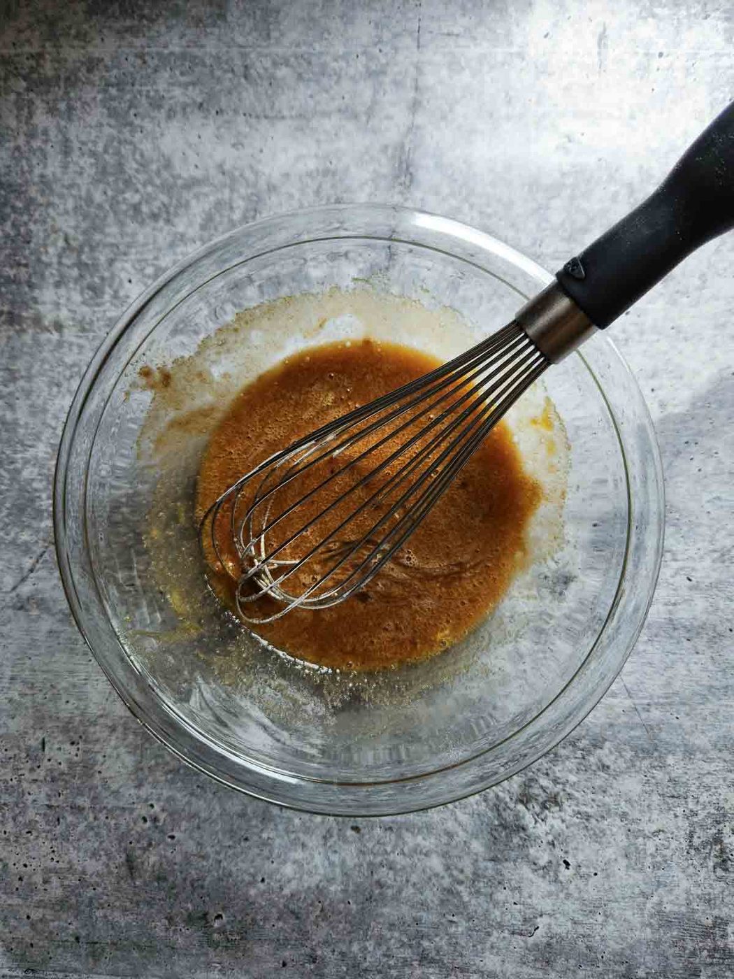 Mixed sugar and eggs in a clear bowl.
