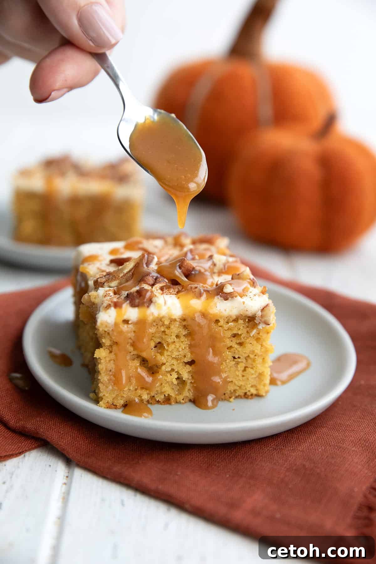 A spoon drizzling keto caramel sauce onto Keto Pumpkin Poke Cake.