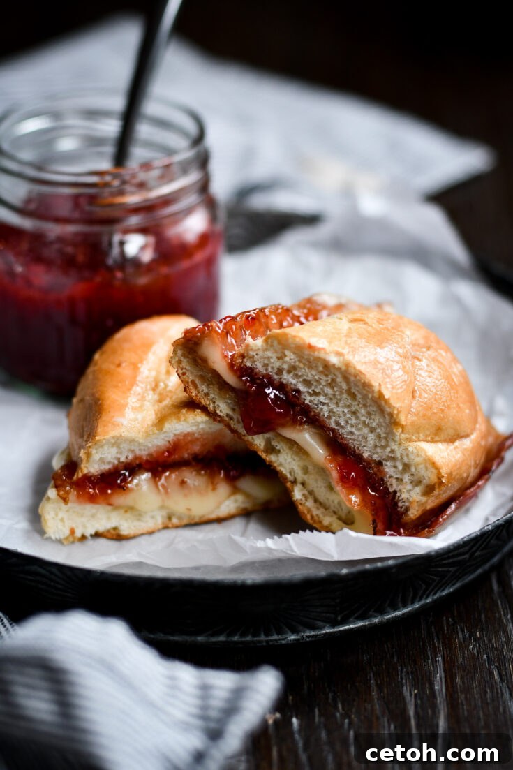 Brie Grilled Cheese with Bacon & Strawberry Jam on a cutting board, ready to serve.