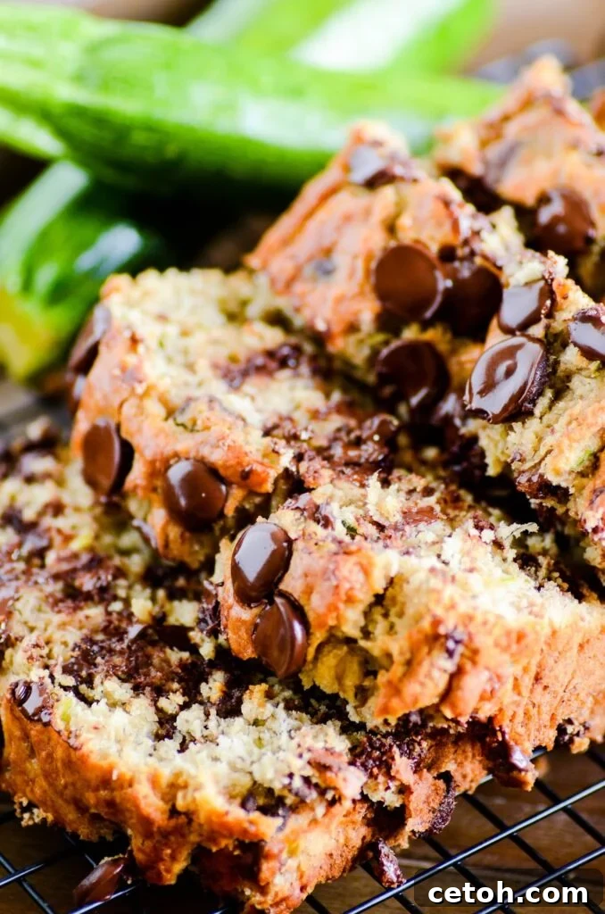 Delicious and moist chocolate chip zucchini banana bread slices on a wooden board, perfect for breakfast or a snack. A great way to use ripe bananas and fresh zucchini.