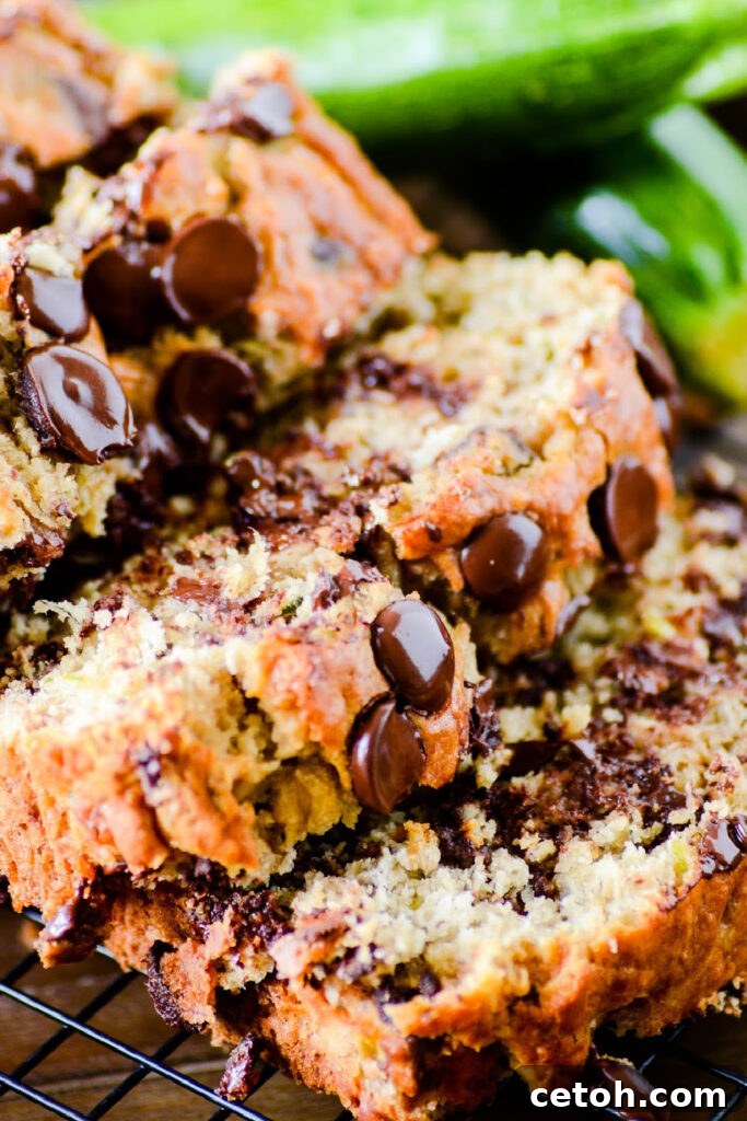 Close-up of a freshly baked loaf of chocolate chip zucchini banana bread on a wire rack, showing its golden crust and delicious texture. The perfect comfort food.