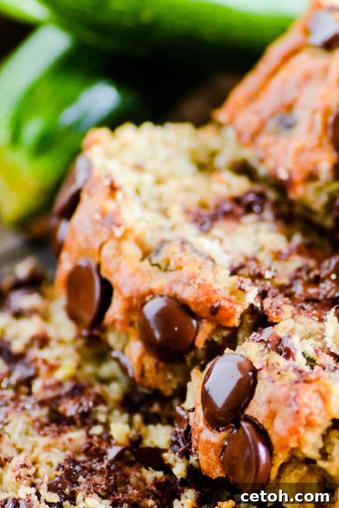 Two slices of chocolate chip zucchini banana bread stacked on a plate, garnished with a sprig of mint. A perfect blend of sweet banana, moist zucchini, and rich chocolate.
