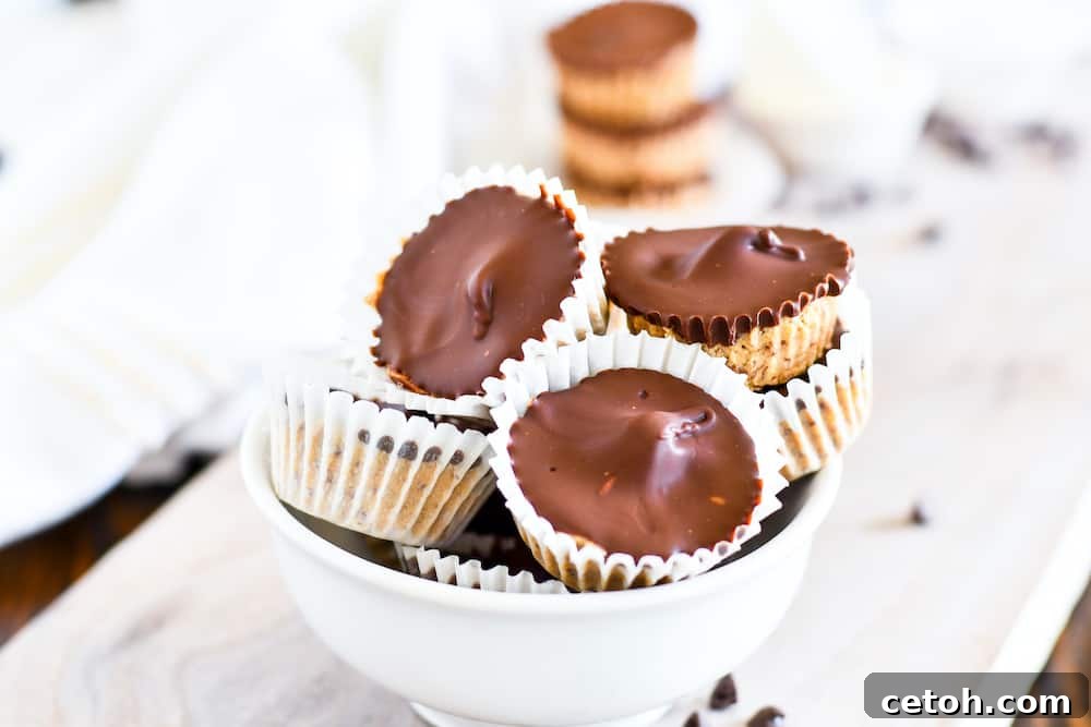 High-Protein Peanut Butter Cups 5 A beautifully composed shot of three protein peanut butter cups, with one cut in half to reveal the creamy, layered interior, emphasizing their homemade quality and tempting appeal.