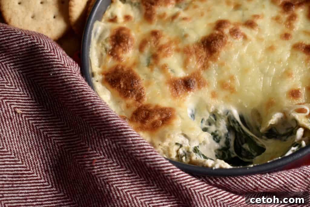 Close up view of the bubbling, golden-brown top of spinach artichoke dip