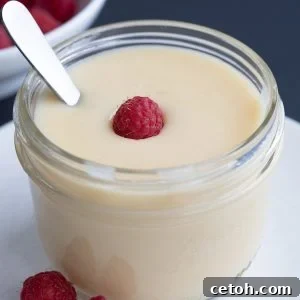 Close up shot of Easy Sugar Free Condensed Milk in a jar with a raspberry on top.