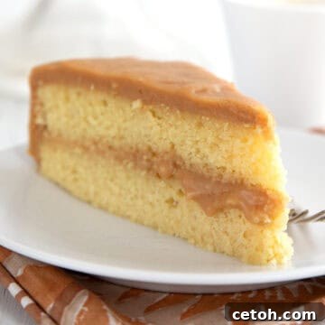 A slice of Keto Caramel Cake on a white plate over a patterned brown napkin.