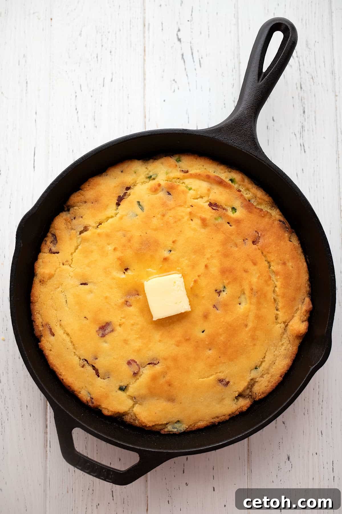 Top down image of keto cornbread in a skillet on a white wooden table.