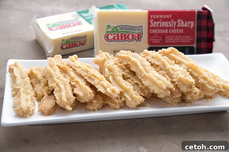 Low carb cheese straws in front of bricks of sharp cheddar cheese. 