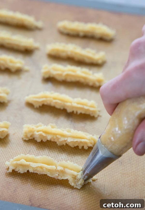 Piping cheese straw dough onto a baking sheet. 