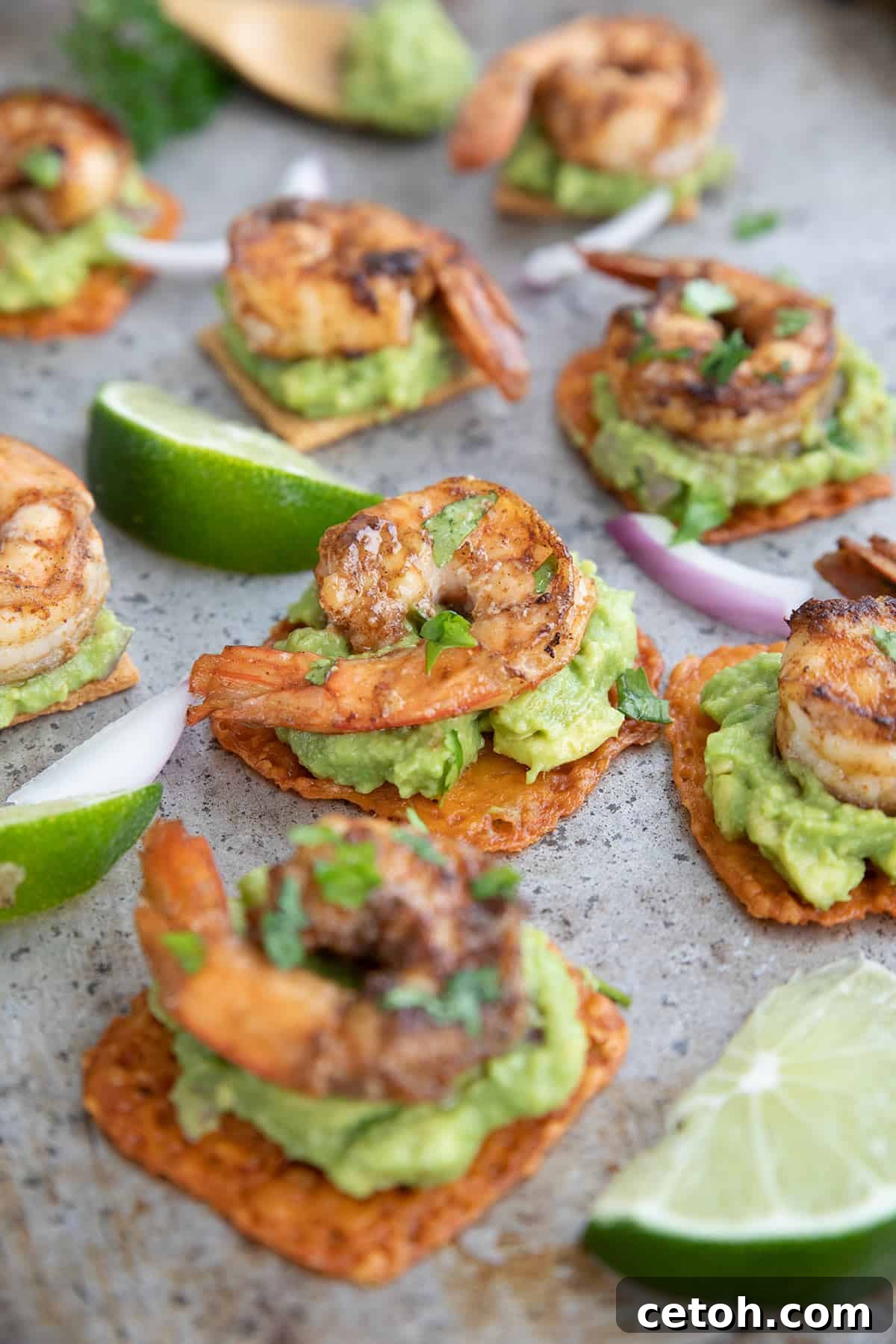 Keto Countdown Nibbles for New Year's Eve 10 Guacamole shrimp bites on a metal baking tray with slices of lime.