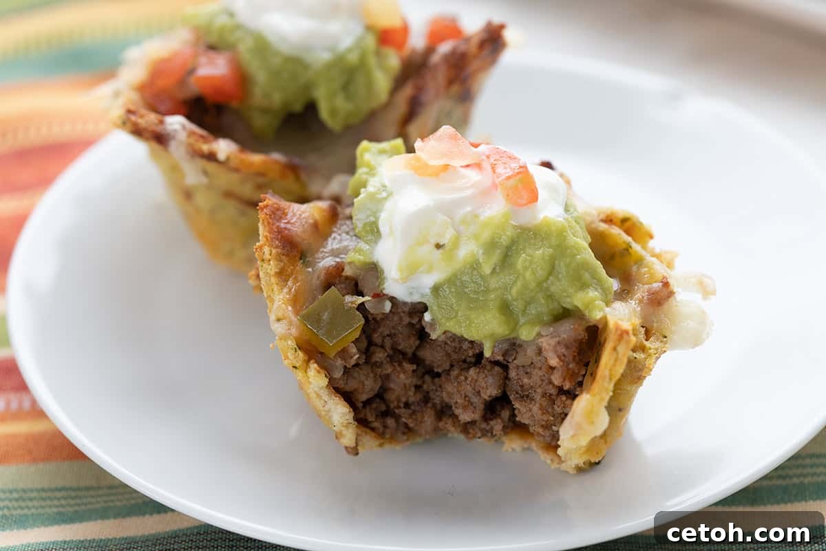 Keto Countdown Nibbles for New Year's Eve 11 Close up shot of keto taco cups on a white plate with a bite taken out of the front one.