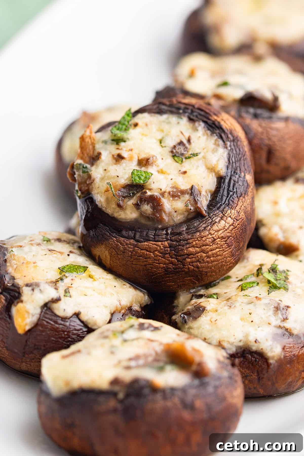 Keto Countdown Nibbles for New Year's Eve 2 Keto Stuffed Mushrooms piled up on a white serving platter.