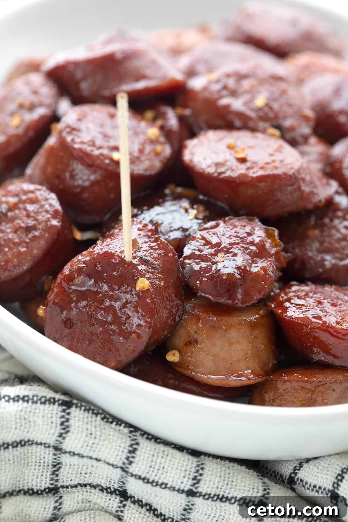 Keto Countdown Nibbles for New Year's Eve 4 Close up shot of kielbasa bites in a white oval dish over a white and black cloth.