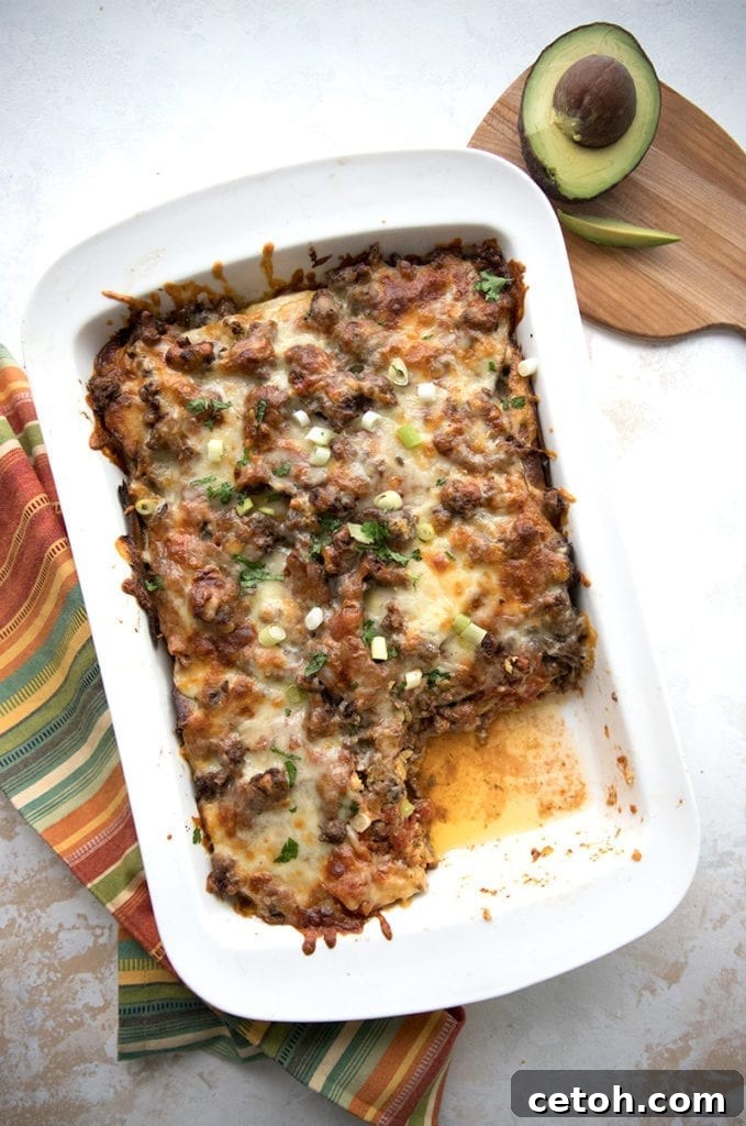 Top down photo of a pan of keto enchilada casserole with a slice taken out. 