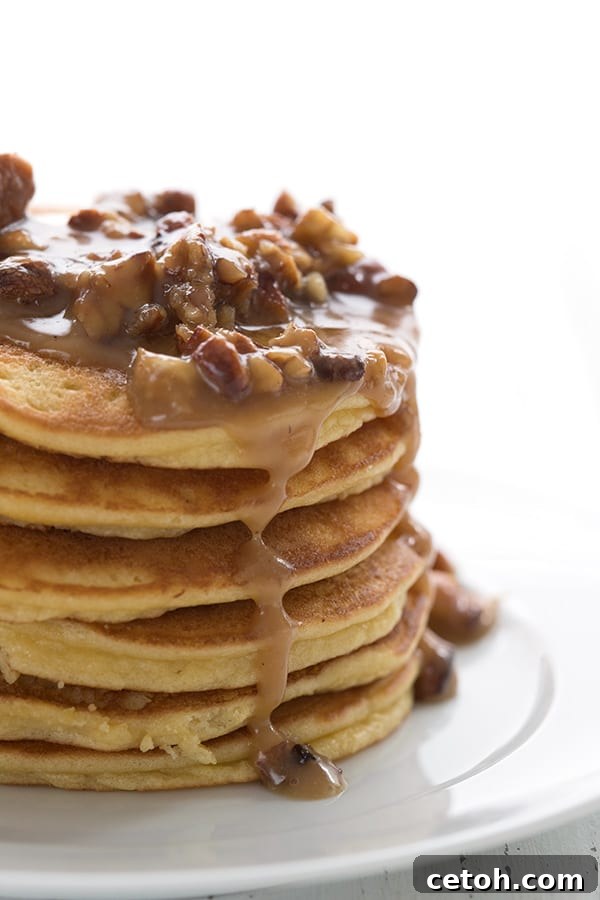 Keto Decadent Pecan Praline Sauce 3 A delectable stack of golden keto almond flour pancakes, generously dripping with homemade Keto Praline Pecan Sauce and adorned with whole pecans.