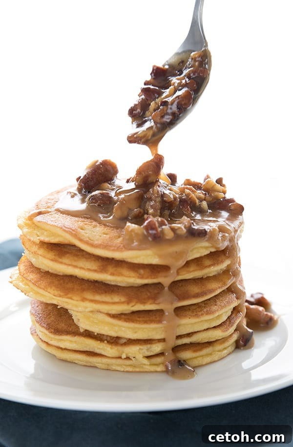 Keto Decadent Pecan Praline Sauce 5 A close-up of thick, gooey keto praline sauce being drizzled over a stack of fluffy almond flour pancakes, making for a perfect low-carb breakfast.