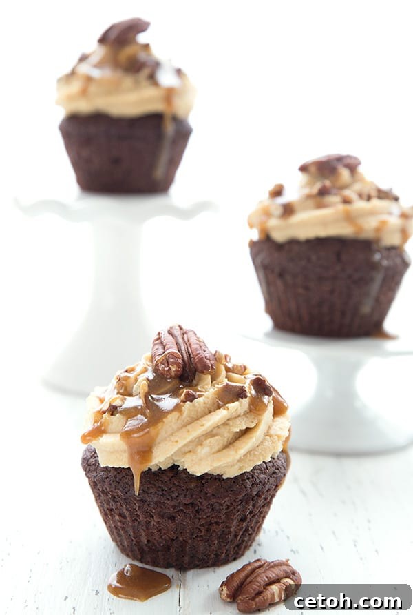 3 keto turtle cupcakes on a white table, two of them on cupcake stands. 