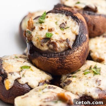 Keto Stuffed Mushrooms piled up on a white serving platter.
