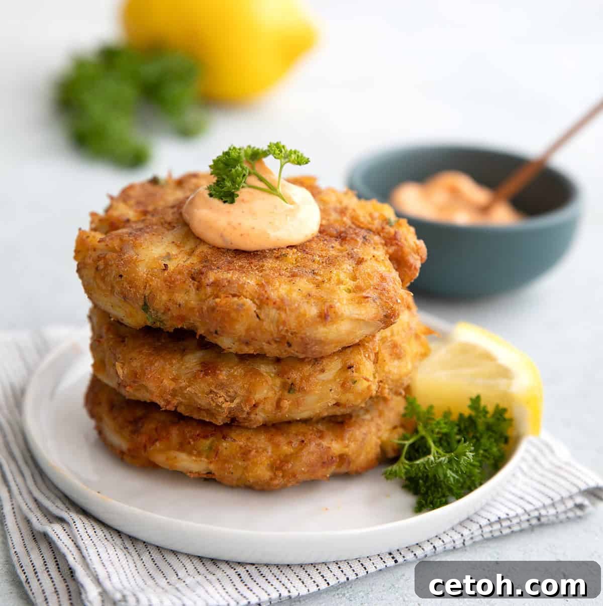 A stack of 3 keto crab cakes on a white plate with a dollop of spicy mayo on top.