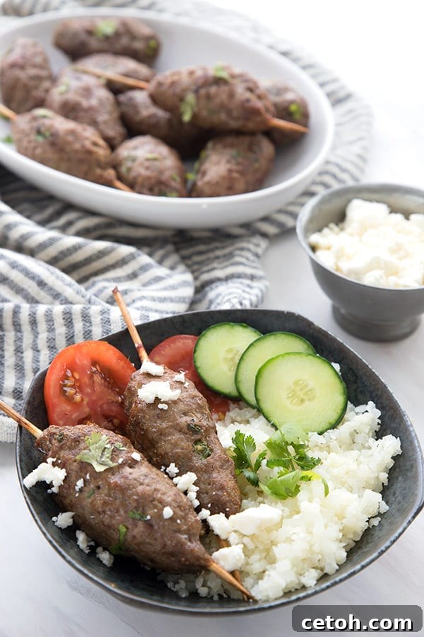 A black bowl filled with succulent air fryer lamb kofta and fluffy cauliflower rice, accompanied by a side dish of fresh kofta on a striped napkin.