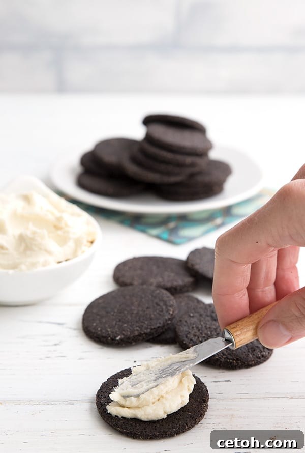 Spreading vanilla cream filling onto a chocolate wafer cookie for homemade keto oreos