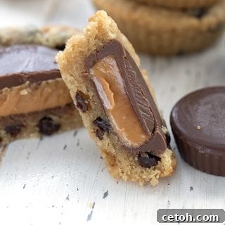Close up shot of a keto cookie stuffed with peanut butter cups cut open to show the inside.