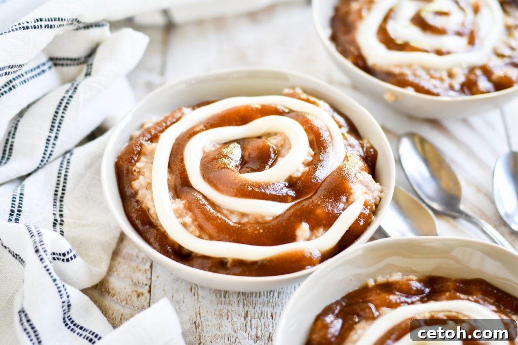 Close-up shot of Cinnamon Roll Oatmeal showing the distinct layers of oatmeal, cinnamon swirl, and cream cheese icing in a beautifully arranged bowl.