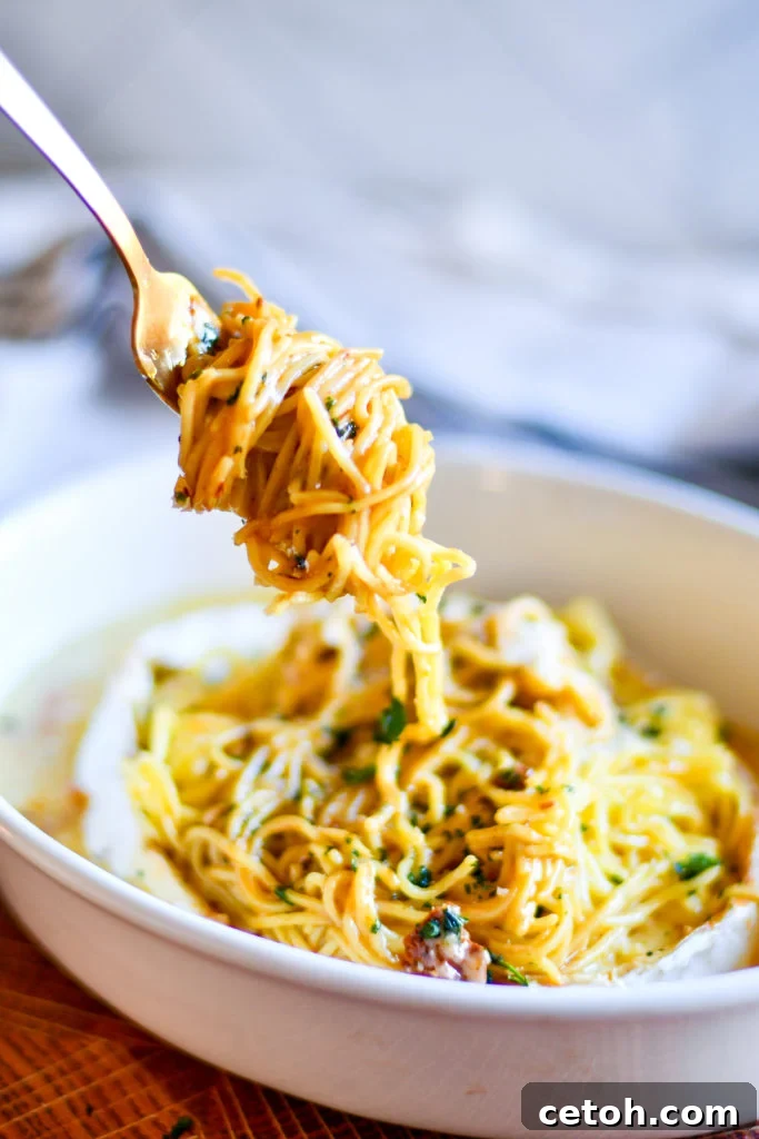 Creamy Baked Brie Spaghetti 2 A close-up shot of creamy Baked Brie Spaghetti, showcasing the melted brie cheese, vibrant sun-dried tomatoes, fresh basil leaves, and perfectly coated pasta strands. The dish is presented in a rustic bowl, ready to be served.
