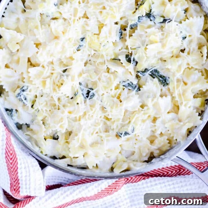A bowl of creamy Spinach Artichoke Bowtie Pasta, garnished with fresh herbs.