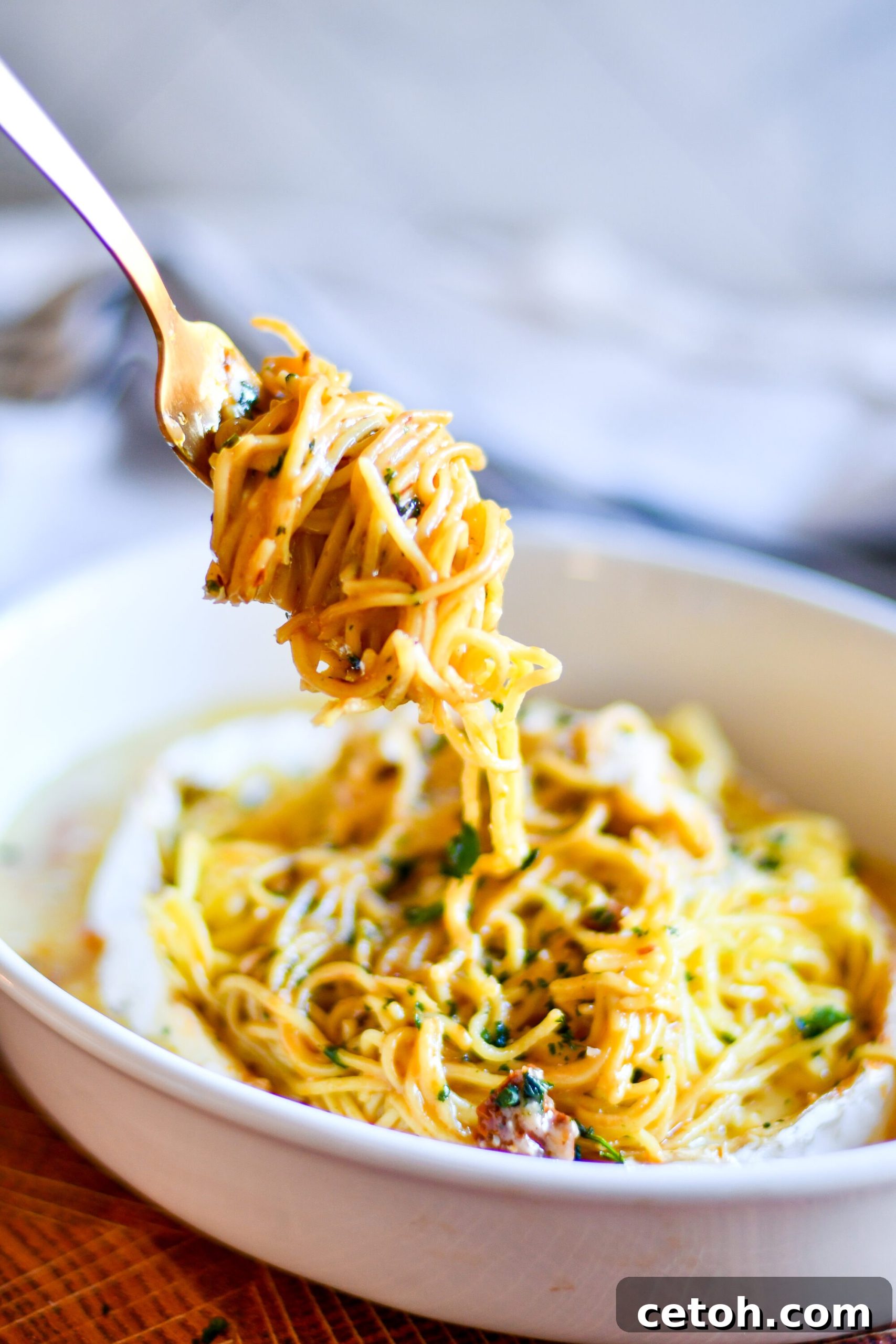 The finished Baked Brie Spaghetti dish, beautifully plated with generous amounts of creamy pasta, sun-dried tomatoes, and basil. It's garnished with extra fresh basil and a sprinkle of red pepper flakes, ready to be enjoyed.