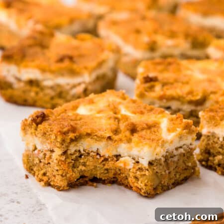 Close up shot of Keto Carrot cake bars on a piece of waxed paper with a bite taken out of the front one.