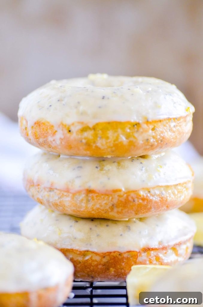 Delicious baked Lemon Poppyseed Donuts, each beautifully adorned with a smooth white lemon glaze and a sprinkling of fresh lemon zest, arranged invitingly on a platter.