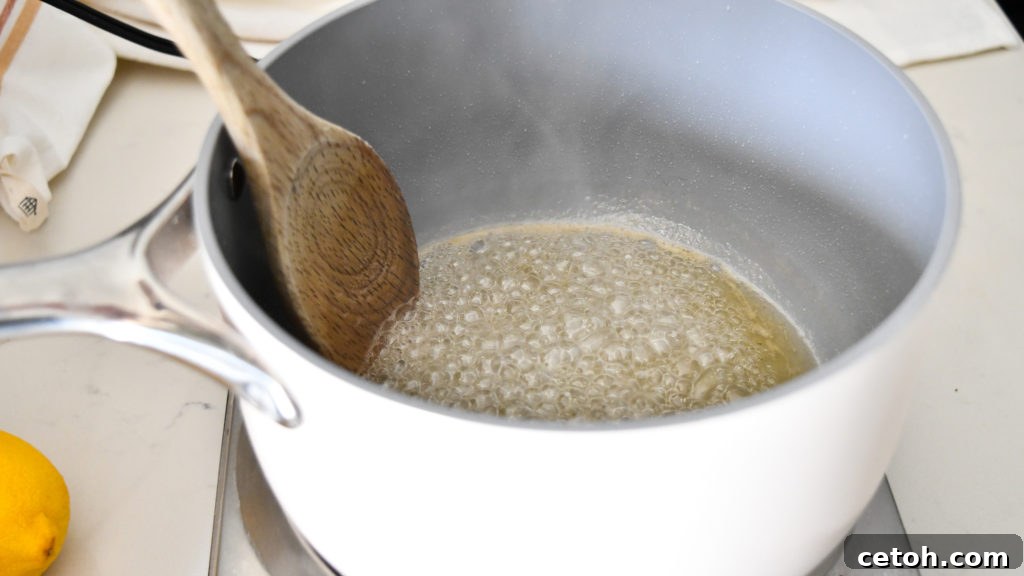 A vibrant lemon simple syrup being poured over a warm, freshly baked cake, visibly soaking into the holes on the cake's surface to enhance moisture and flavor.