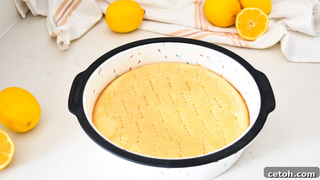 Close-up of the warm lemon syrup glistening on the surface of the cake, with liquid visibly absorbed into the cake's crumb, promising an exceptionally moist result.
