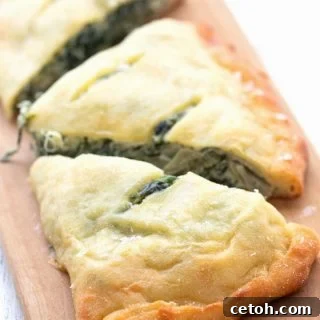 Titled image of a keto spinach artichoke calzone on a cutting board, cut into three pieces.