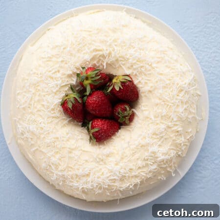 Keto Coconut Cloud Cake 2 Top down image of a keto coconut bundt cake on a white plate with strawberries piled up in the center.