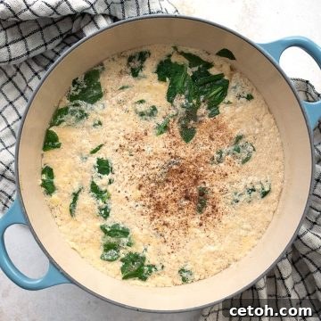Top down image of stracciatella soup in a blue Dutch oven over a checked tea towel.