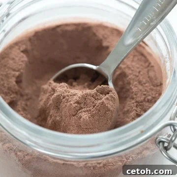 Close up shot of homemade sugar free hot chocolate in a glass jar with a measuring spoon.